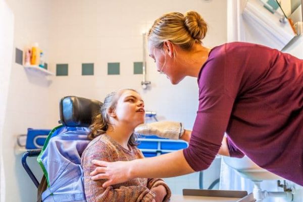 Young girl in a wheelchair gaining support from a caregiver